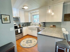 A kitchen with white cabinets, a stainless steel oven, a sink, and a tiled backsplash. - Quiet Home in the Woods, Minutes to Campus with a Gorgeous Back Porch!  (Oxford)