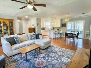 A spacious living room with a sofa, coffee table, and patterned rug. A dining area with a table and chairs is visible in the background. - Quiet Home in the Woods, Minutes to Campus with a Gorgeous Back Porch!  (Oxford)