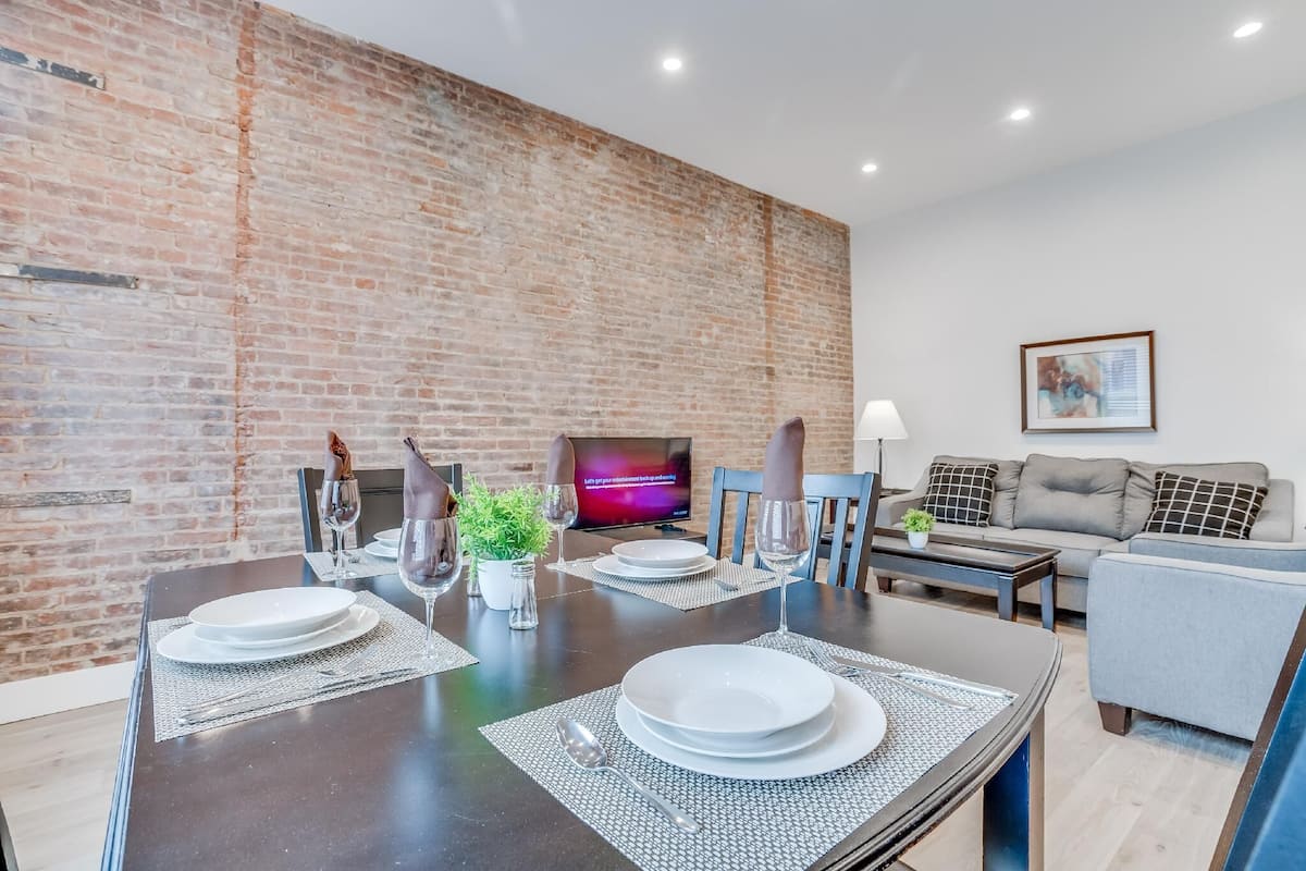 A modern dining area with a brick wall, a television, and a sofa.