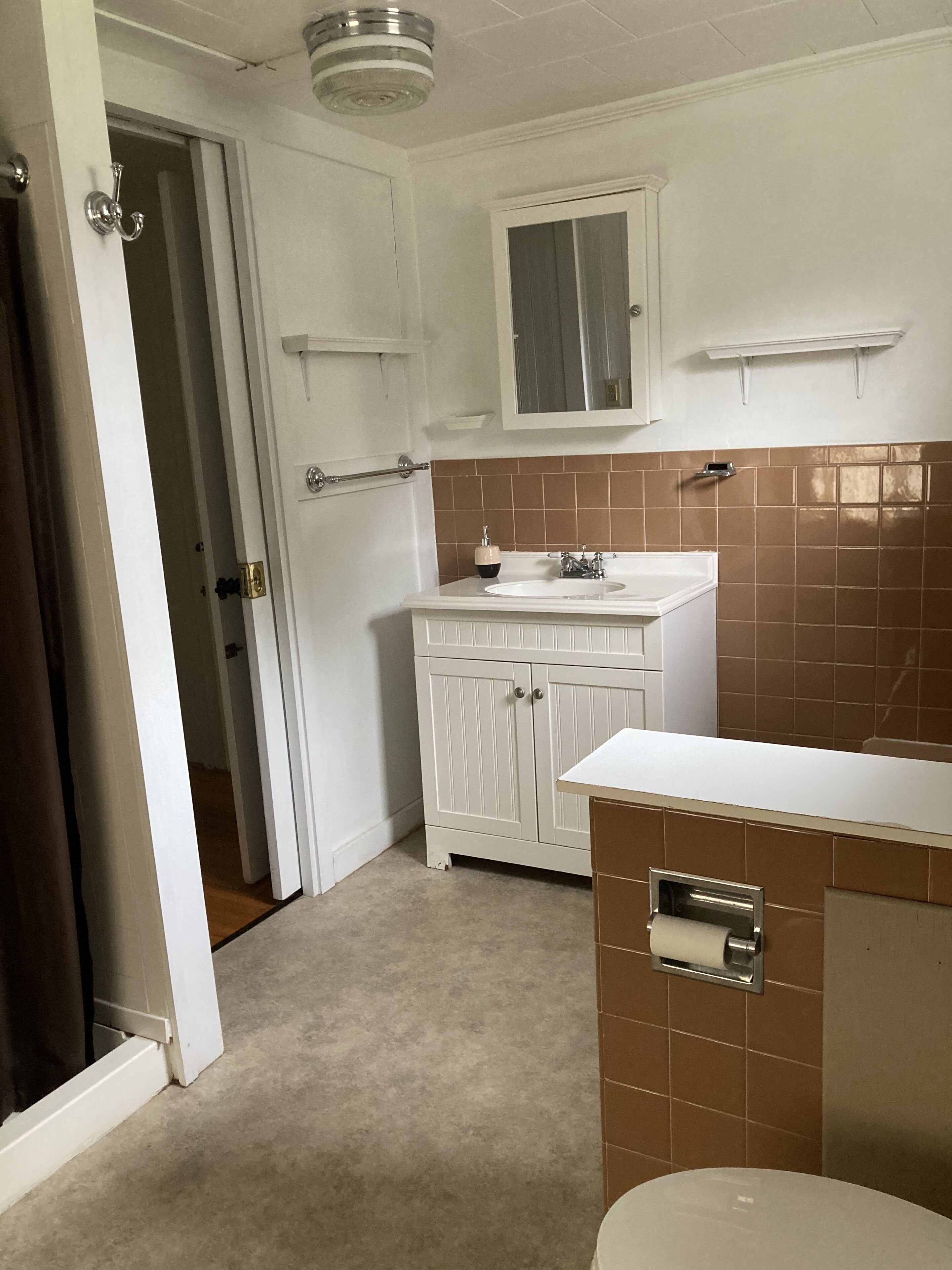 Een badkamer met een wit wastafelmeubel, een spiegel en een toilet.
