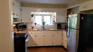 A kitchen with white cabinets, a stainless steel refrigerator, a microwave, and a stove.