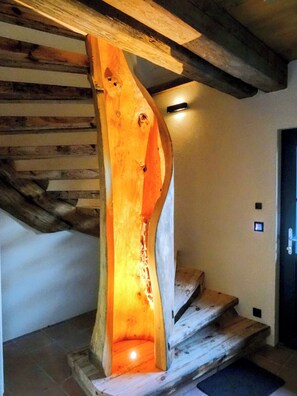 A wooden staircase with a unique, curved design and a light source at the bottom.