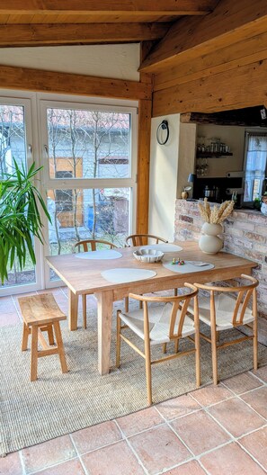 A wooden dining table with benches, a potted plant, and a view of the outside.