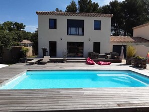 Une maison moderne à deux étages, dotée d’une piscine, d’un espace salon extérieur et d’un patio.