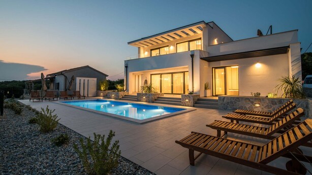 A modern two-story house with a swimming pool, outdoor seating, and a well-lit entrance. - Luxury Villa Stiletta with Pool (Krk)