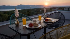A table with breakfast items and drinks on a balcony overlooking a sunset and landscape. - Luxury Villa Stiletta with Pool (Krk)