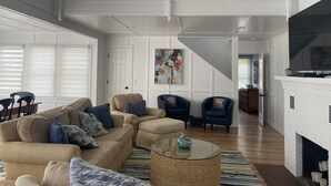 A spacious living area with a high ceiling, a fireplace, and a balcony with a railing. - BEAUTIFUL LAKE MICHIGAN BEACH HOUSE just a 5-minute walk to the water’s edge! (Muskegon)