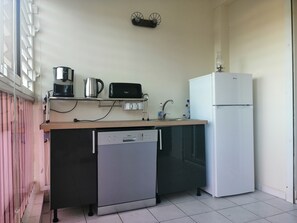 Uma cozinha compacta com máquina de lavar louça, geladeira branca, cafeteira e torradeira.