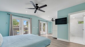 A bedroom with a bed, a ceiling fan, a TV, and a sliding glass door leading to a patio. - Pet Friendly Beach Cottage - Walk to the Beach Gated Access - Fenced in Yard - Bidawee (Panama City Beach)