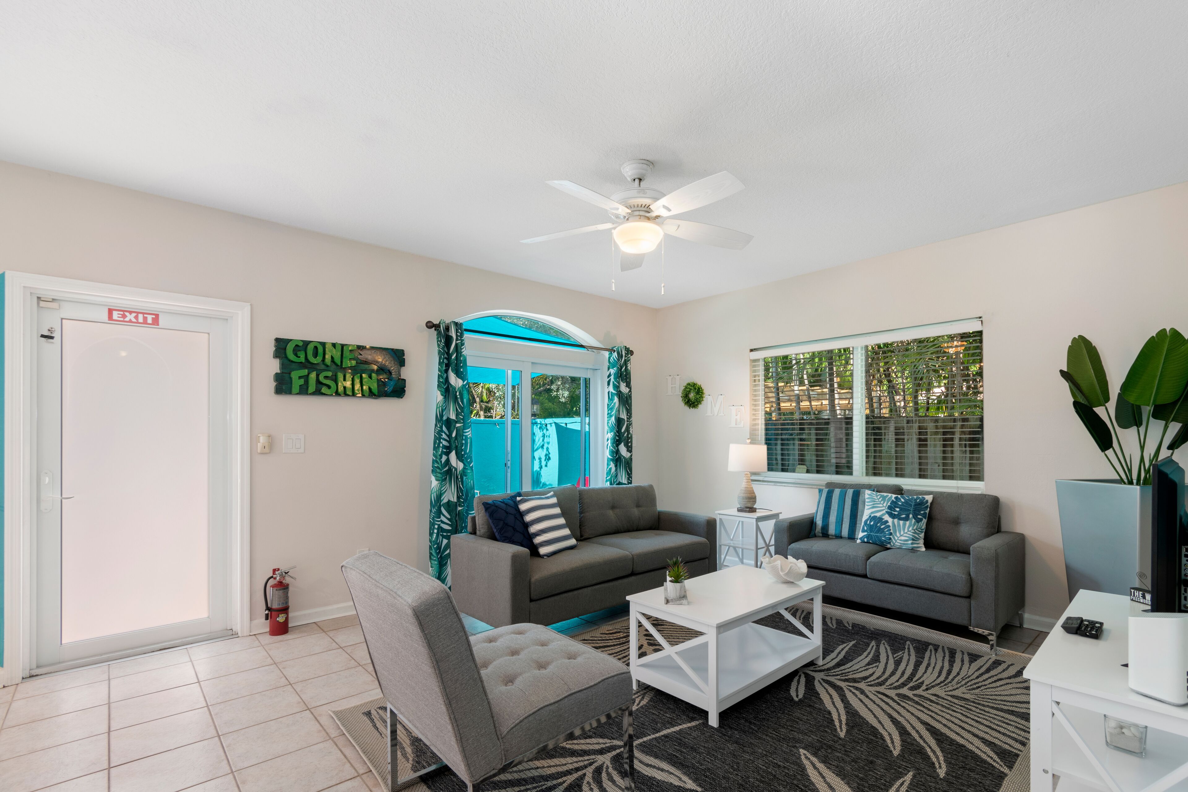 A living room with two grey sofas, a white coffee table, and a ceiling fan.