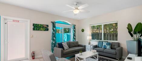 A living room with two grey sofas, a white coffee table, and a ceiling fan.