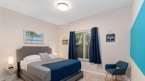 Une chambre à coucher comprenant un lit, une table de chevet, une chaise, une fenêtre avec des rideaux et des éléments décoratifs sur les murs.