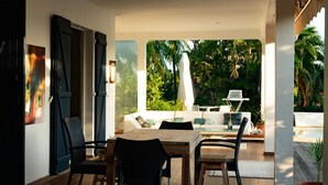 An open-plan living area with a dining table and chairs, a sofa, and a view of a tropical garden. - Exceptional property in a lush setting (Case-Pilote)