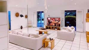 A modern living room with white sofas, a flat-screen TV, and a wooden coffee table. - Exceptional property in a lush setting (Case-Pilote)
