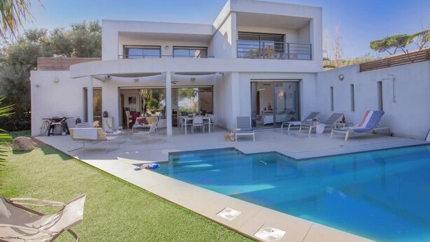 A modern two-story house with a swimming pool, outdoor seating, and a covered patio.