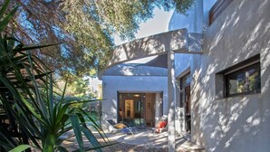 A modern house with a curved exterior, a glass door entrance, and a patio with outdoor seating.