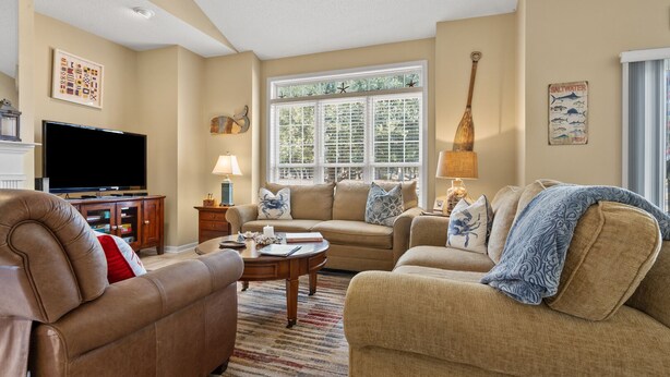 A living room with a flat-screen TV, two sofas, a coffee table, and a window with blinds. - Modern golf course townhome w/pool, close to many golf courses, shops, restaurants in North Myrtle (North Myrtle Beach)