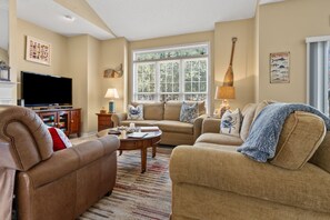 A living room with a flat-screen TV, two sofas, a coffee table, and a window with blinds. - Modern golf course townhome w/pool, close to many golf courses, shops, restaurants in North Myrtle (North Myrtle Beach)