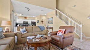 A living room with a sofa, armchair, coffee table, and a patterned rug. - Modern golf course townhome w/pool, close to many golf courses, shops, restaurants in North Myrtle (North Myrtle Beach)