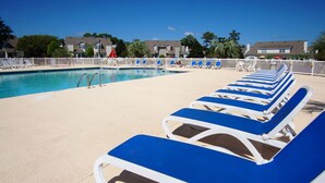 A pool area with blue and white lounge chairs arranged in rows, a pool with clear blue water, and a white fence surrounding the area. - Modern golf course townhome w/pool, close to many golf courses, shops, restaurants in North Myrtle (North Myrtle Beach)