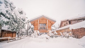 A wooden cabin with a balcony, surrounded by snow-covered trees and a wooden fence. - Charming chalet in Les Praz de Chamonix near the Flégère's cable car (Chamonix-Mont-Blanc)