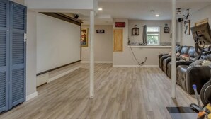 Una habitación amplia con piso de madera, un ventanal grande, una caminadora y una silla de masajes.