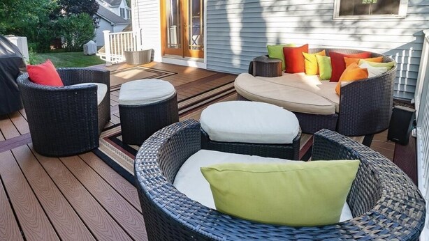 Una terraza con mobiliario de mimbre, incluyendo sillas y un sofá, y una pequeña mesa.