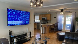 Una sala de estar moderna con una mesa de centro de vidrio, sofá de cuero y un televisor de pantalla plana que muestra un llamado a la acción para un servicio.