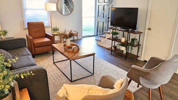 Uma sala de estar moderna com sofá, poltrona, mesa de centro e aparador para TV.
