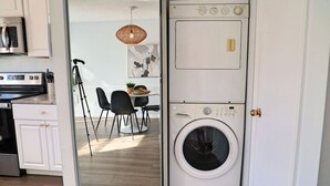 Uma cozinha compacta com armários brancos, micro-ondas e máquina de lavar.