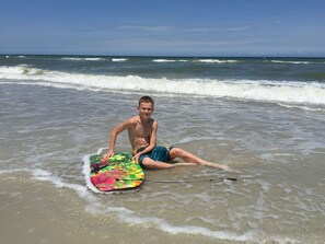 A person sitting on the beach with a colorful boogie board.