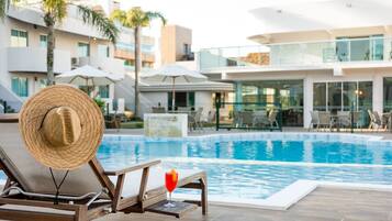 Zona de piscina con una tumbona, un sombrero de paja y una bebida.