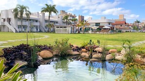 A modern building with a swimming pool, surrounded by greenery and palm trees. - Makkai Resort Bombinhas (Bombinhas)