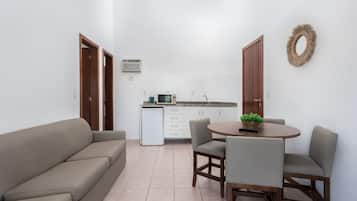 Um espaço compacto para viver, com sofá, mesa de jantar, cadeiras, uma cozinha compacta e um frigorífico pequeno.