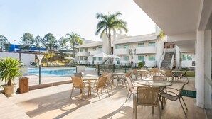 A poolside area with outdoor seating and a view of a building with multiple balconies. - Makkai Resort Bombinhas (Bombinhas)
