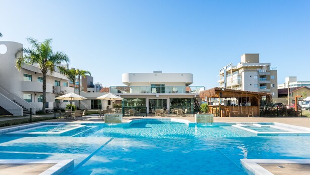 A modern hotel with a swimming pool, outdoor seating, and a bar area. - Makkai Resort Bombinhas (Bombinhas)