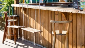 A wooden bar area with a thatched roof, a wooden stool, and a bottle of Corona beer. - Makkai Resort Bombinhas (Bombinhas)