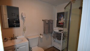 Et badeværelse med toilet, vask og brusekabine i glas.