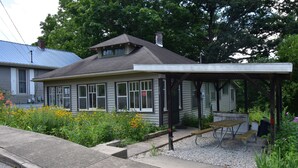 Et hus med en overdækket veranda, en lille have med gule blomster, og nummer '859' synligt på huset.