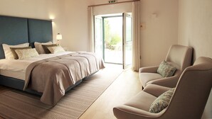 A bedroom with a bed, a chair, and a door leading to a balcony. - Quinta da Luz - A Luxury Boutique B&B (Silves)
