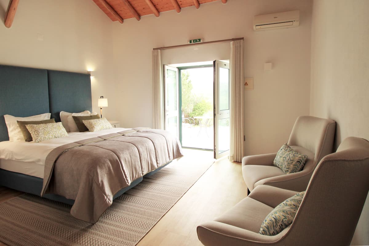 Un dormitorio con una cama, una silla y una puerta que da a un balcón.