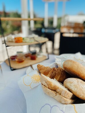 Una mesa con panadería y pasteles, una bandeja con alimentos, y vista al exterior.