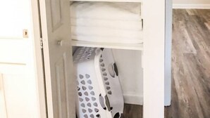 Siisti kaappi, jossa on taitellut valkoiset pyyhkeet ja pyykkikori.