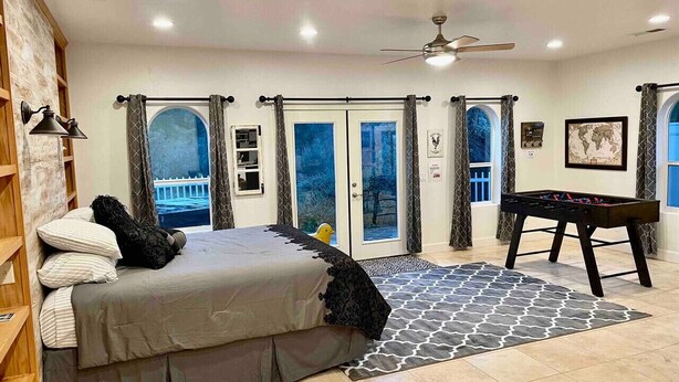A bedroom with a bed, a foosball table, and a view of the outside. - The Funky Chicken - Hot Tub - BBQ - Sleeps 4 (Ahwahnee)