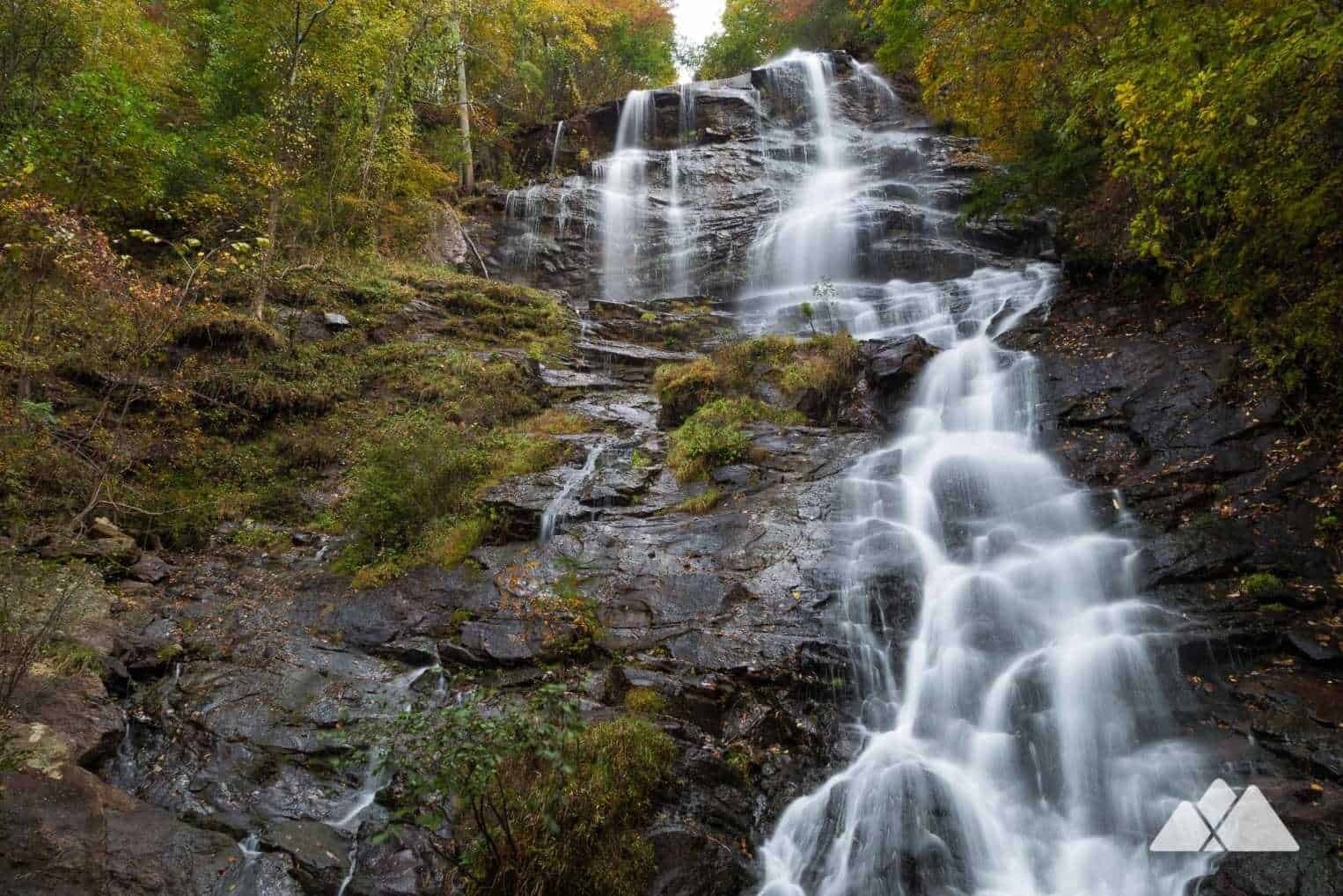 A waterfall cascading over rocky terrain surrounded by dense forest.
