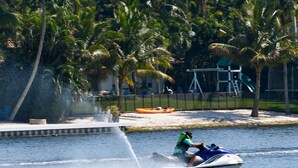 Un jet ski acuático con una persona a bordo, generando una gran cantidad de agua salpicando.