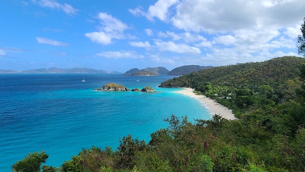 A coastal landscape with clear turquoise waters, a sandy beach, and lush green hills. - Echo @Serendip Vacation Condos (Cruz Bay)