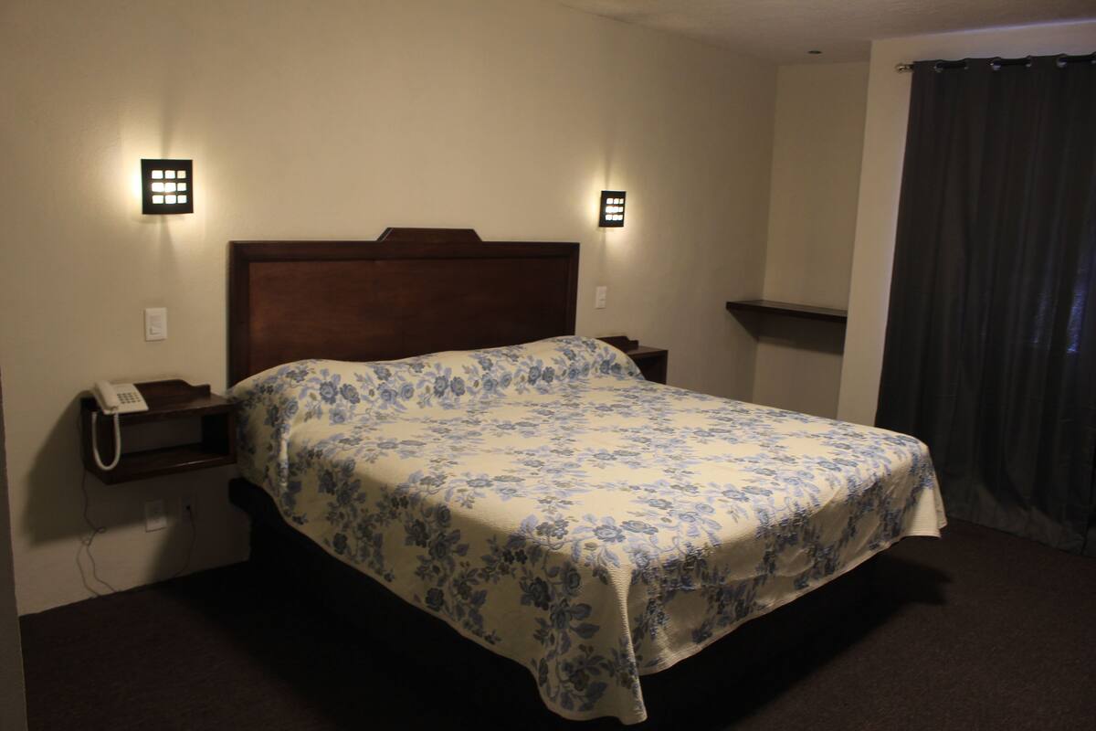 A neatly made bed with a floral bedspread, bedside lamps, and a telephone on the nightstand.
