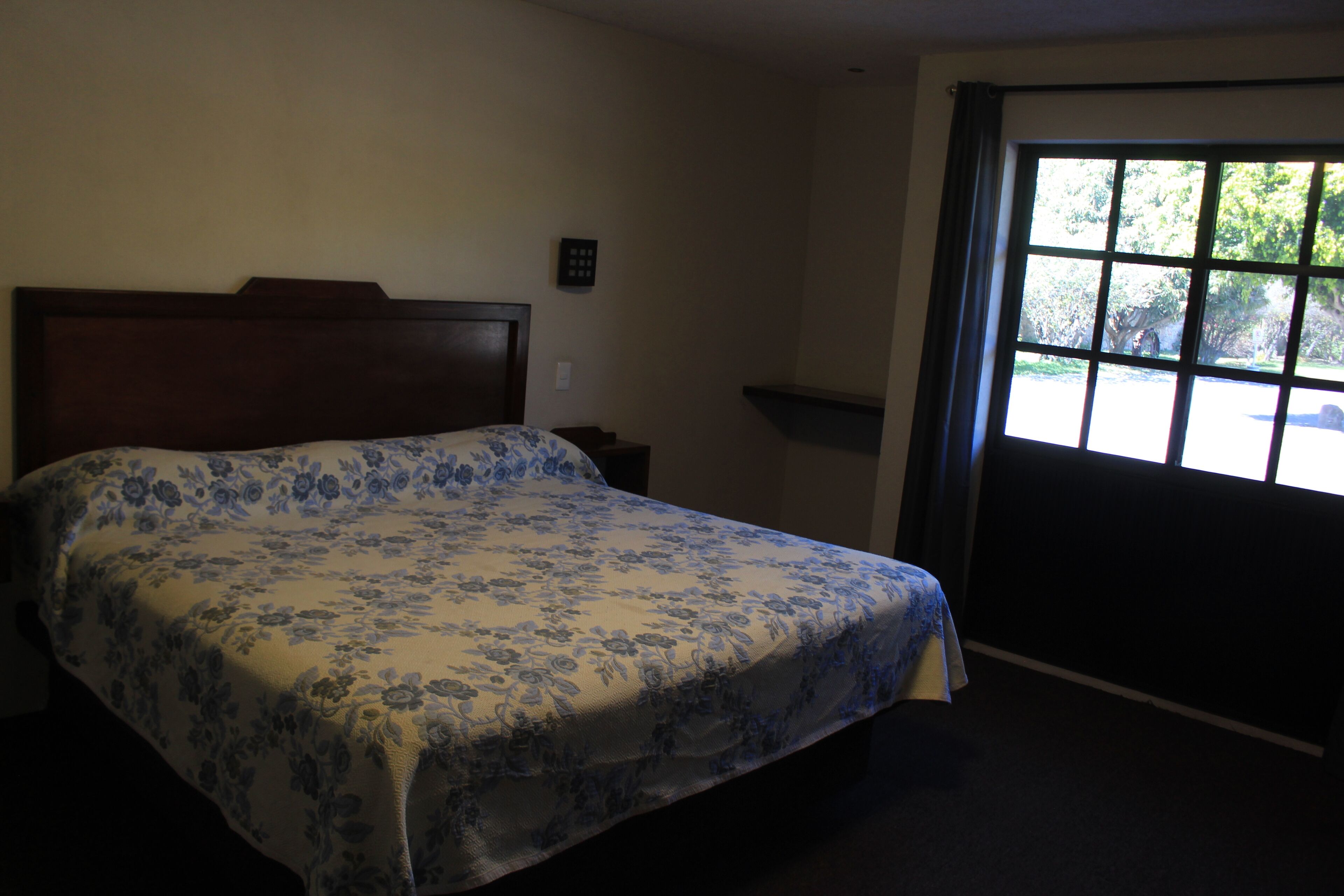 A bedroom with a bed, a nightstand, a window, and a door.