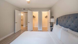 A bedroom with a bed, a ceiling fan, and a nightstand with a lamp. - Stylish 2BR Near UT Hyde Park Evonify (Austin)